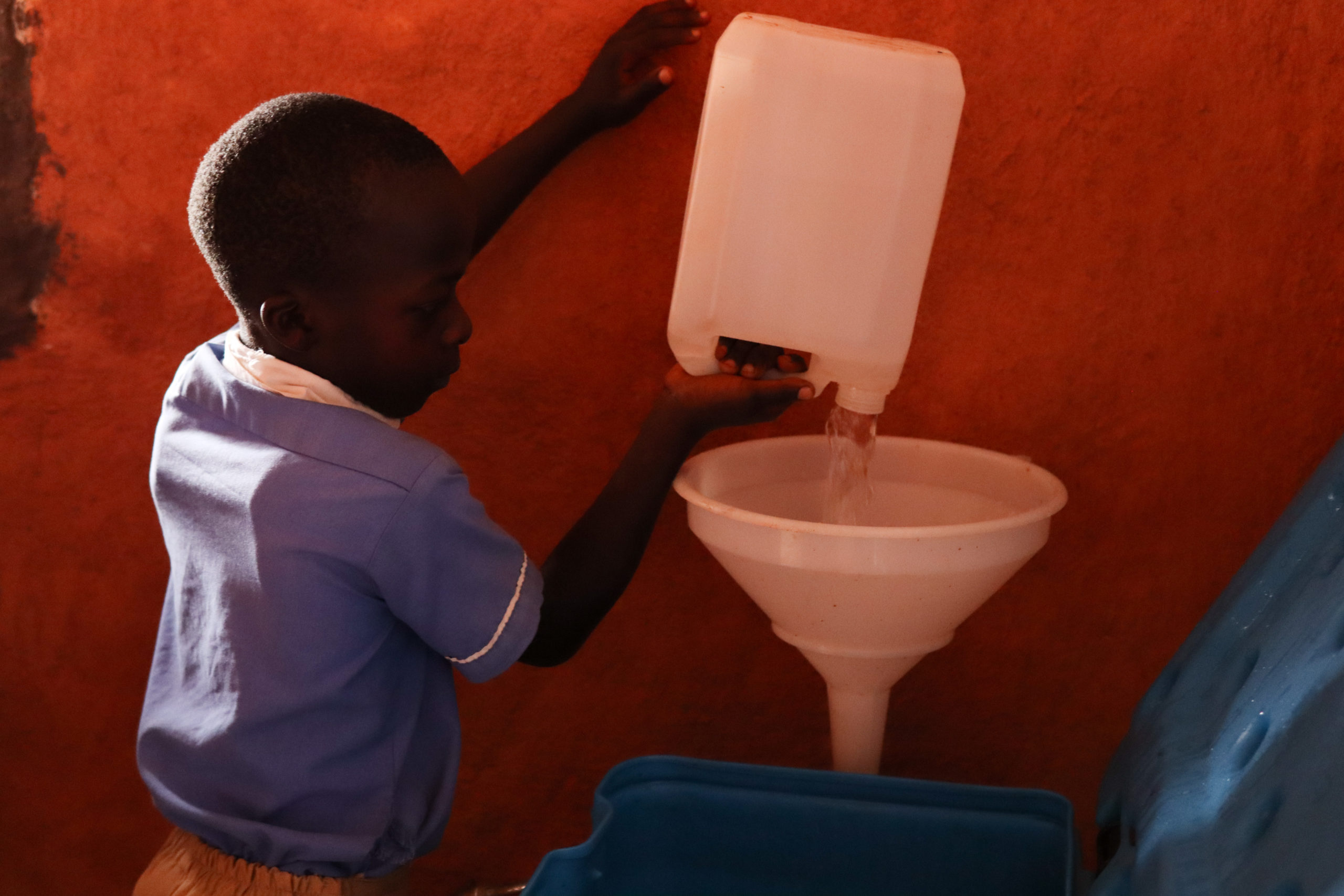 Ein Schüler des Open Gate Learning Centers schüttet Wasser in den Wasserfilter