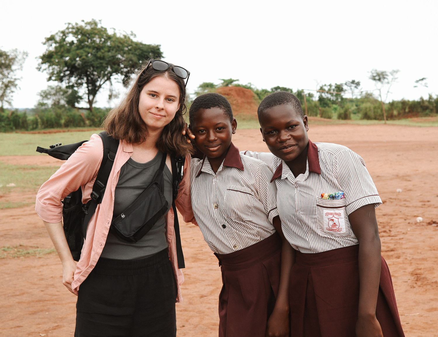 WeWater Mitarbeiterin Gina und zwei Schplerinnen der Kigumbya School posen für ein Foto.